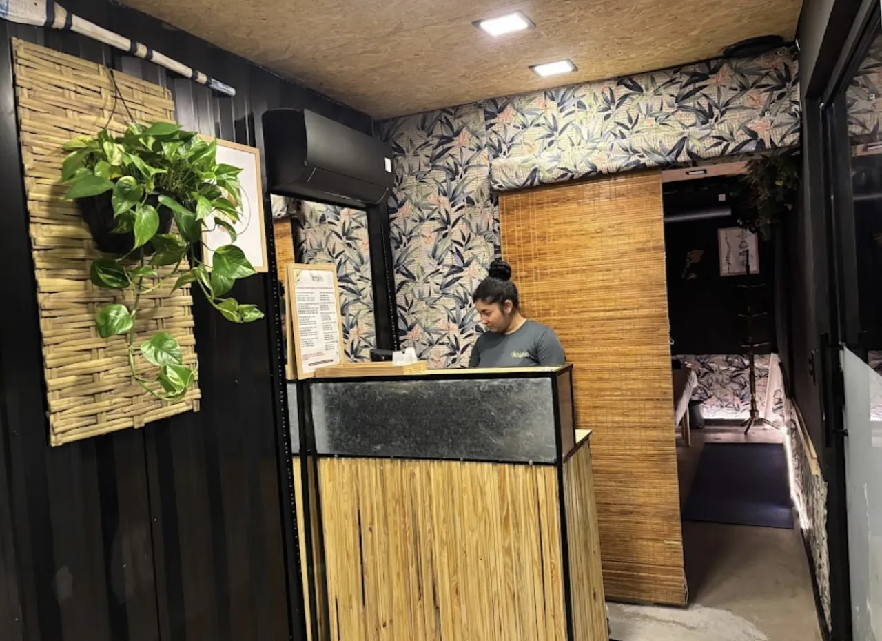 Recepção da unidade Consolação, com balcão e parede decorada com folhas e bambu